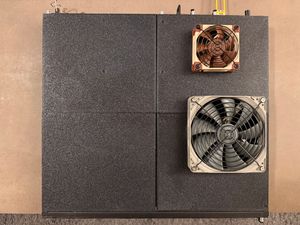 The finished product: fans and 3D-printed lid panels installed. A top-down view of the same switch on a table, with its lid replaced by four custom 3D-printed panels. Two of the panels on the right side have computer case fans mounted externally to the switch, with grilles protecting the exposed side of the fan.